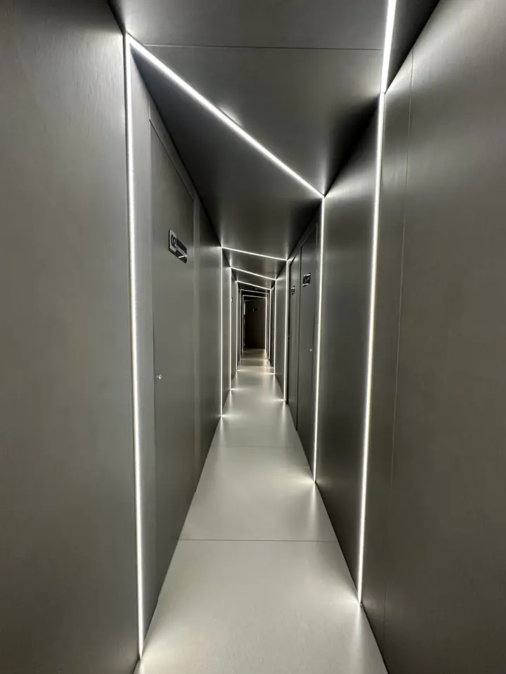 Corredor da clínica com frisos de luz nas arestas e portas individuais.